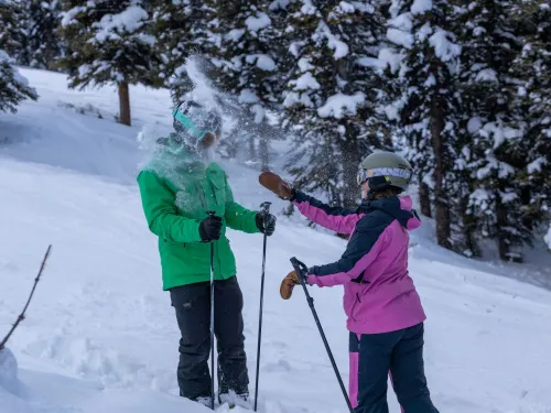 A women throwing a snowball at her friend on the ski hill