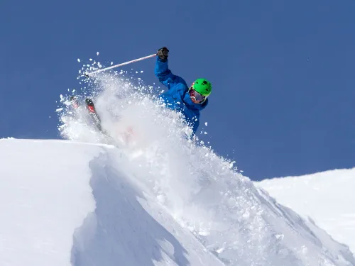 A skier carving powder on a snow peak