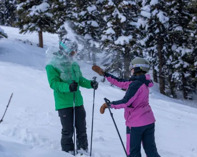 A women throwing a snowball at her friend on the ski hill