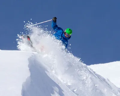 A skier carving powder on a snow peak